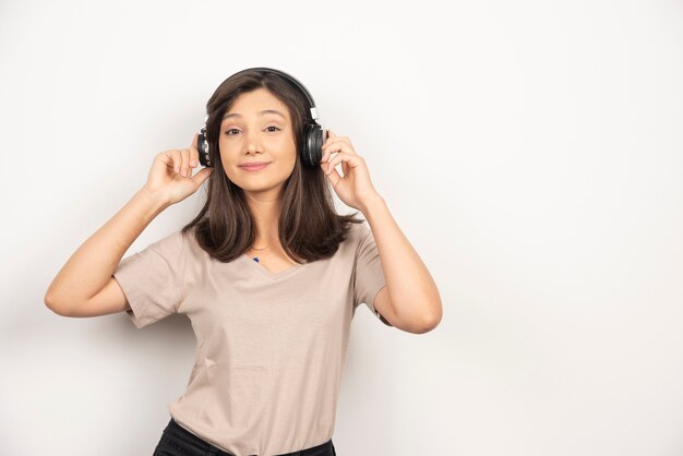 Mujer bonita joven que se divierte escuchando música con auriculares inalámbricos.