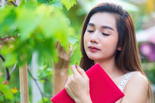 Mujer bonita joven que mira el árbol de uva con felicidad