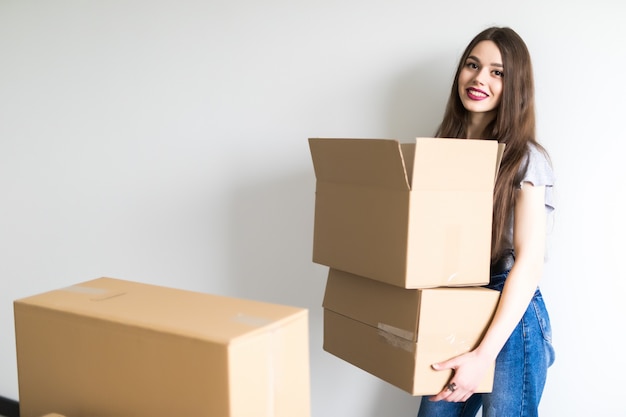 Mujer bonita joven que se muda a un nuevo apartamento con cajas de cartón con pertenencias