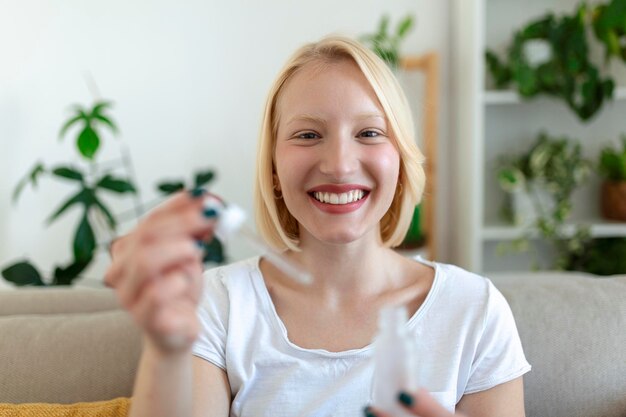 Mujer bonita joven que recibe un tratamiento especial para la piel en casa Chica hermosa que aplica suero para los ojos Piel suave sin arrugas