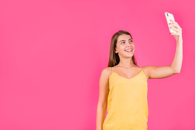 Mujer bonita joven que sonríe y que toma el selfie