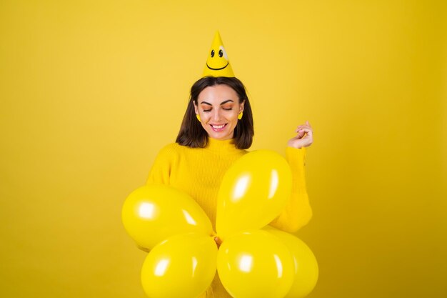 Mujer bonita joven en un suéter amarillo con globos celebra el mejor cumpleaños del trigésimo cumpleaños