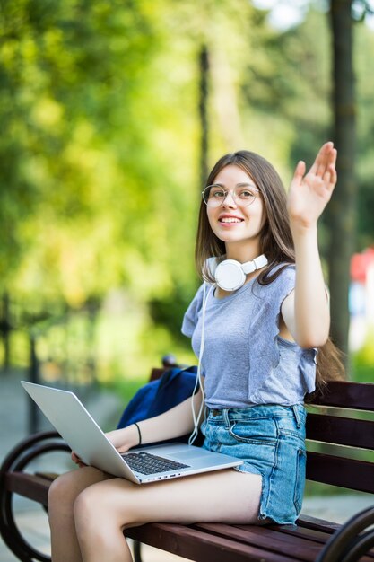 Mujer bonita joven trabajando en el parque y saludando en el parque