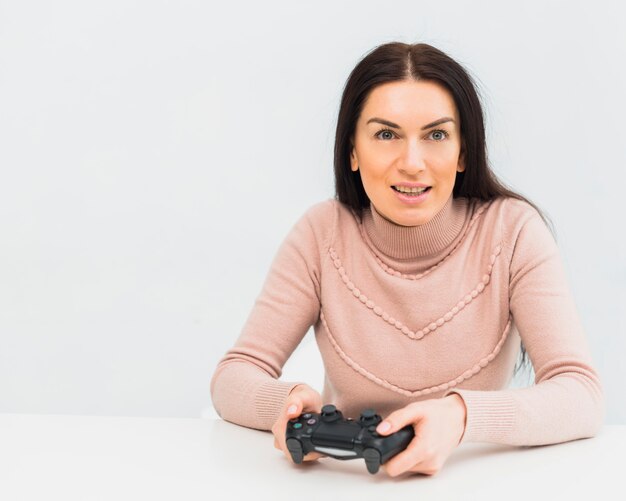 Mujer bonita jugando consola de juegos en la mesa