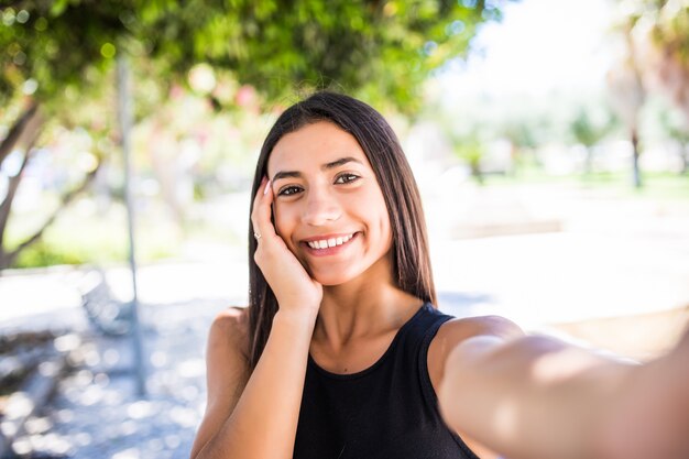 Mujer bonita latina con sonrisa encantadora mirando a la cámara mientras está de pie en la calle