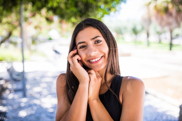 Foto gratuita mujer bonita latina con sonrisa encantadora mirando a la cámara mientras está de pie en la calle
