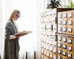 Foto gratuita mujer bonita leyendo cerca de la ventana de la biblioteca