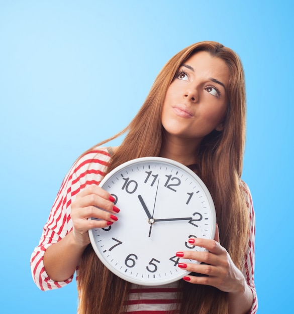 Mujer bonita mirando hacia arriba sosteniendo un reloj