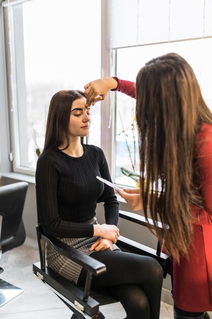 Mujer bonita modelo en salón de belleza está haciendo maquillaje de noche