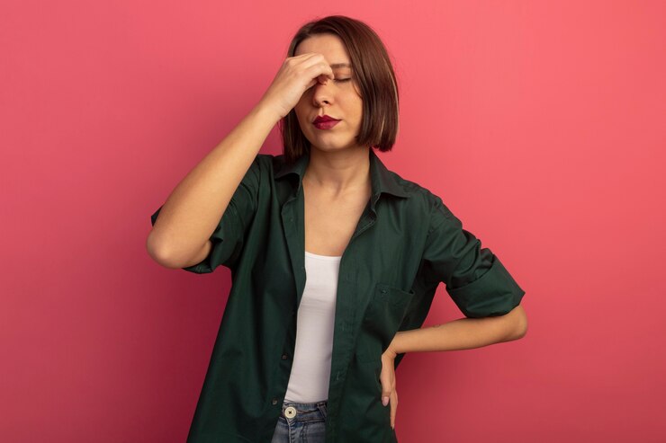 Foto gratuito mujer bonita molesta se encuentra con los ojos cerrados poniendo la mano en la nariz aislada en la pared rosa
