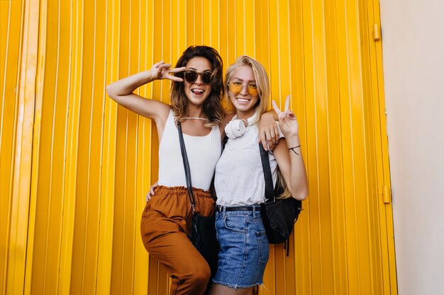 Mujer bonita morena posando emocionalmente con su amiga rubia.