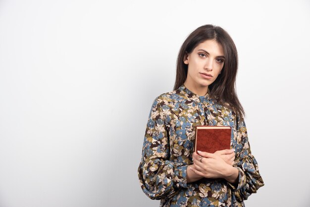 Mujer bonita morena sosteniendo un libro.