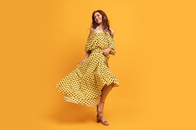 Mujer bonita pelirroja en vestido amarillo posando en amarillo. Estado de ánimo de verano