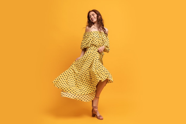 Mujer bonita pelirroja en vestido amarillo posando en amarillo. Estado de ánimo de verano