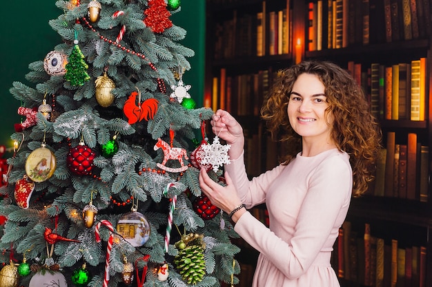 La mujer bonita se prepara árbol de Navidad que se coloca en la habitación