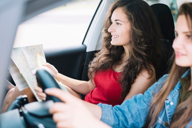 Mujer bonita que mira el mapa mientras que monta el coche