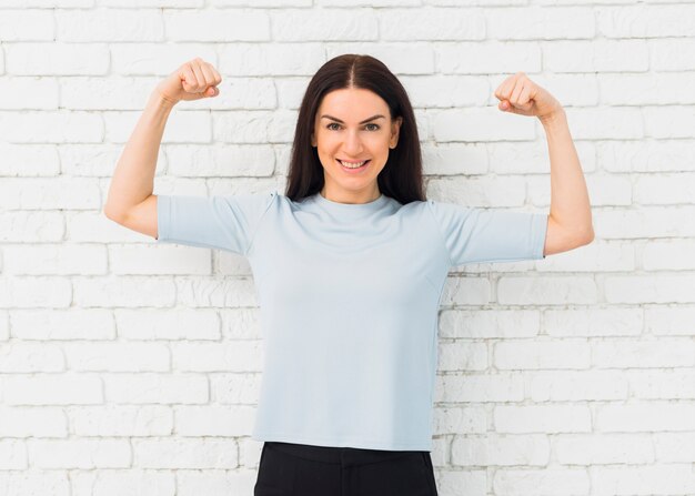 Mujer bonita que muestra los músculos del brazo sonriendo