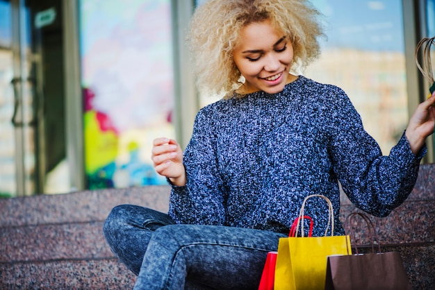 Mujer bonita que se sienta con las bolsas vivas