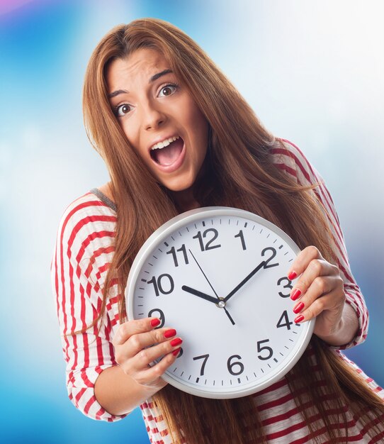 Mujer bonita que sostiene el reloj.