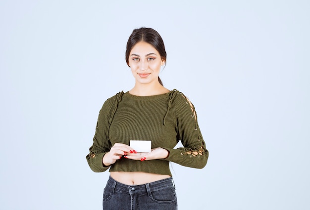 Mujer bonita que sostiene la tarjeta de visita en blanco sobre fondo blanco.