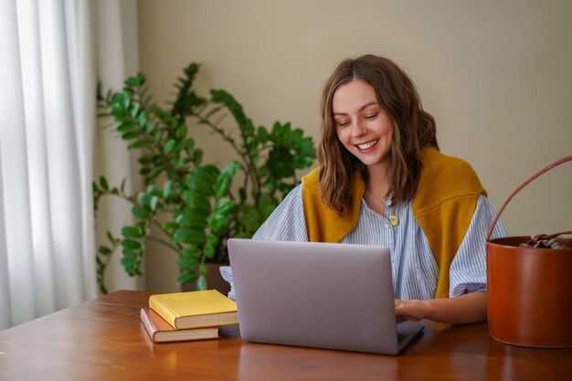 Mujer bonita que trabaja en su oficina en casa, sonriendo y disfrutando del tiempo en su sala de estar.