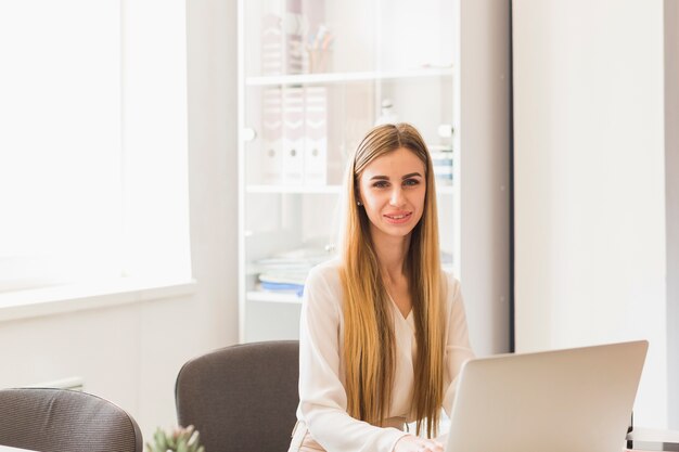 Mujer bonita que usa la computadora portátil en la oficina