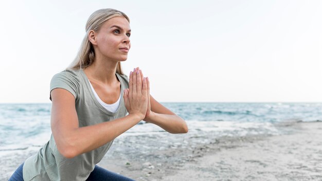 Mujer bonita rubia practicando yoga al aire libre