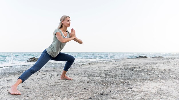 Mujer bonita rubia practicando yoga al aire libre