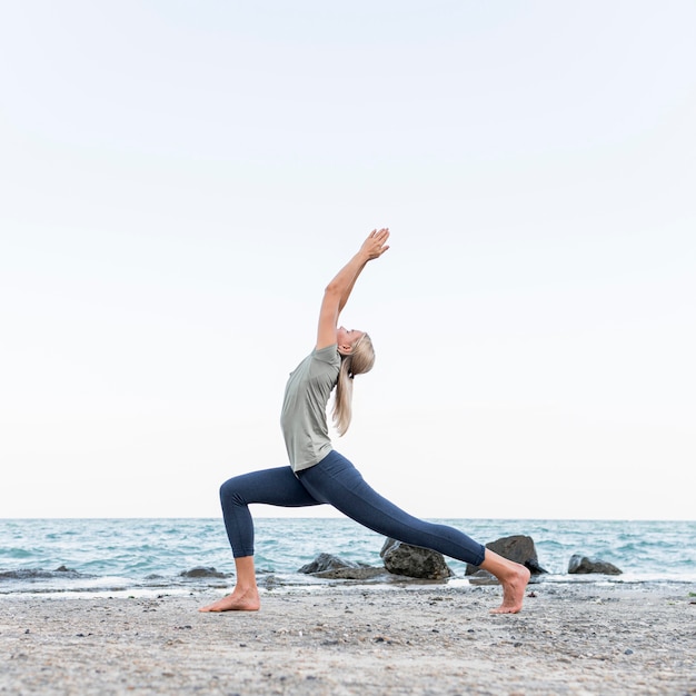 Foto gratuita mujer bonita rubia practicando yoga al aire libre