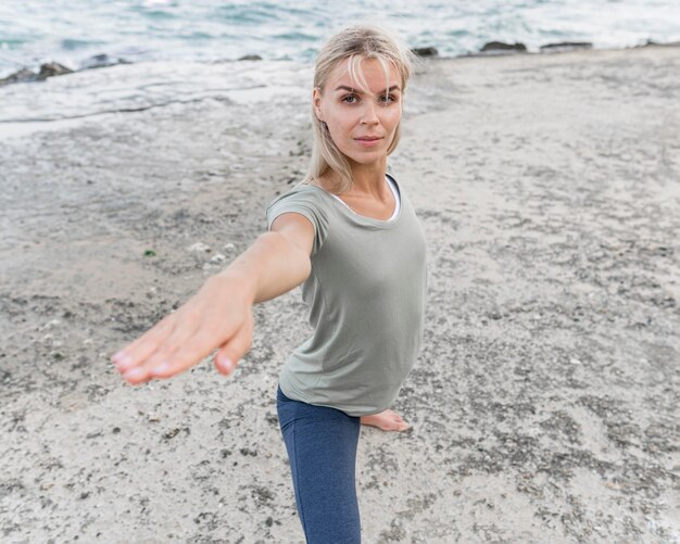 Mujer bonita rubia practicando yoga al aire libre