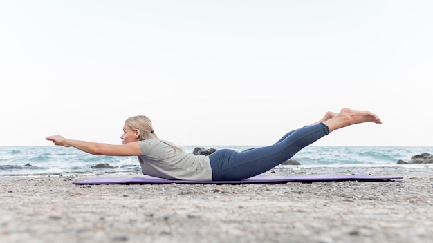 Mujer bonita rubia practicando yoga al aire libre