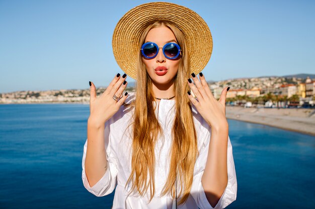 Mujer bonita rubia con sombrero de paja de moda y gafas de sol azules