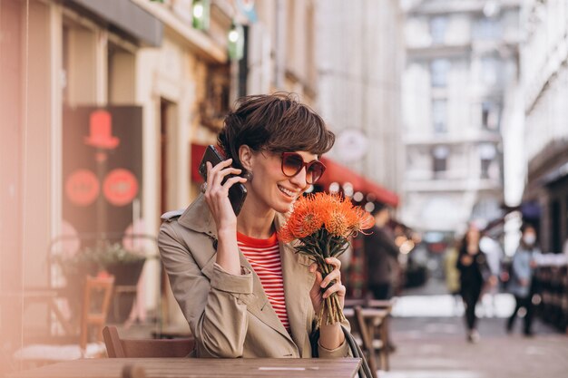 Mujer bonita sentada en un café en la ciudad de China y hablando por teléfono