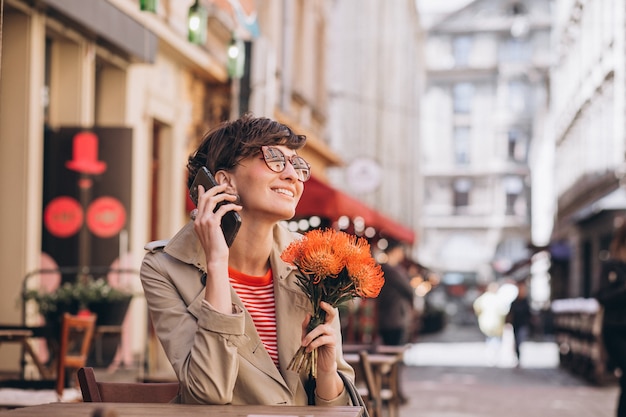 Mujer bonita sentada en un café en la ciudad de China y hablando por teléfono