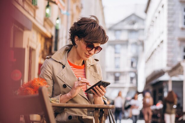 Mujer bonita sentada en un café en la ciudad de China y hablando por teléfono