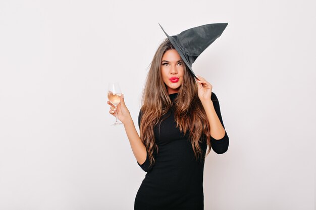 Mujer bonita con sombrero de carnaval bebiendo champán