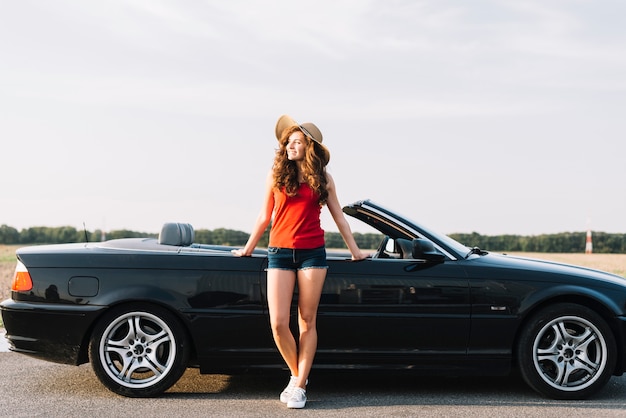 Mujer bonita con sombrero cerca de cabriolet