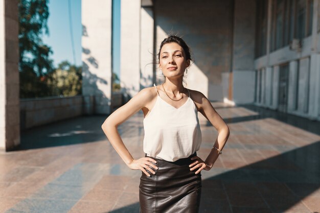 Mujer bonita sonriente que lleva a cabo las manos en las caderas mientras que presenta