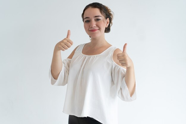 Mujer bonita sonriente que muestra los pulgares para arriba