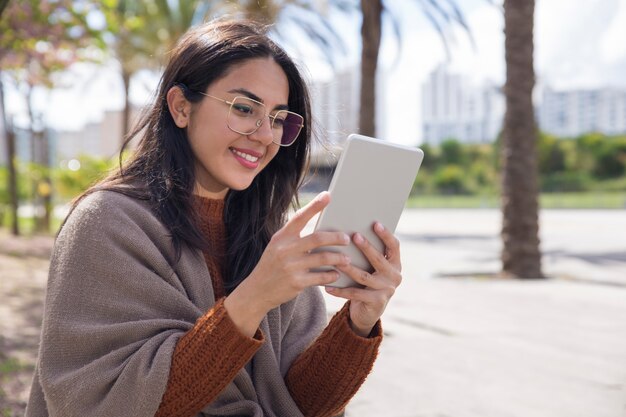 Mujer bonita sonriente que usa la tableta al aire libre