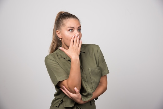 Mujer bonita sorprendida por algo en la pared gris.