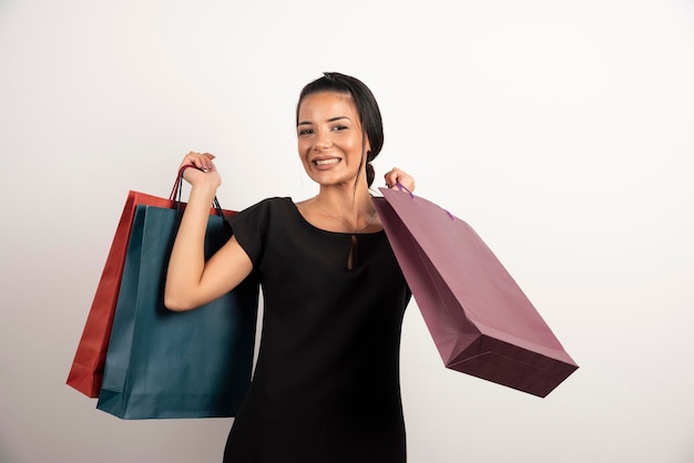 Mujer bonita sosteniendo bolsas de la compra en la pared blanca.