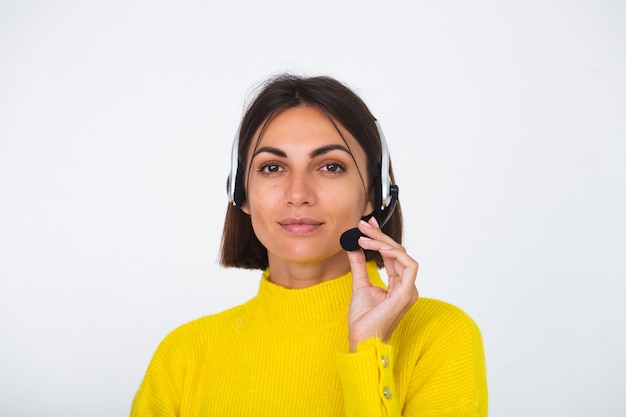 Mujer bonita en suéter amarillo en gerente blanco con auriculares feliz sonrisa de bienvenida positiva