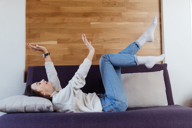 La mujer bonita en suéter blanco y jeans azules se divierte en mal día