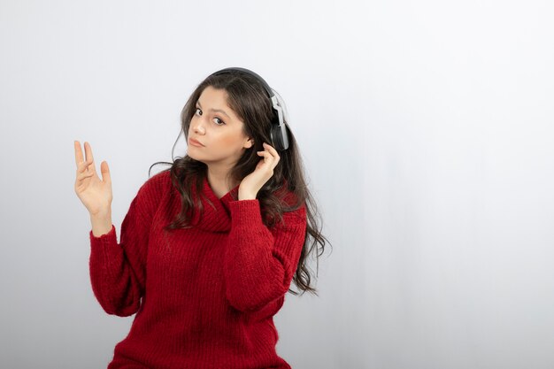 Mujer bonita en suéter disfrutando de la música a través de auriculares inalámbricos mientras escucha su melodía favorita.