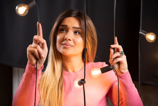 Una mujer bonita en suéter mirando lámparas de luz.