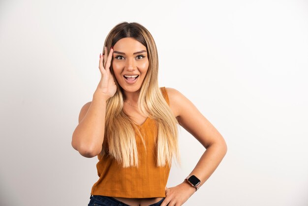 Mujer bonita tocando su cabeza y posando sobre fondo blanco.