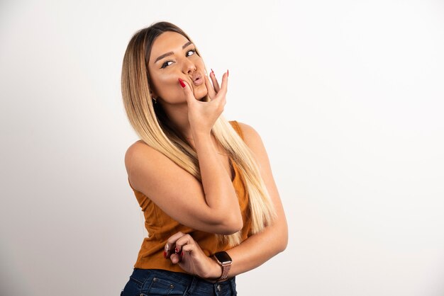 Mujer bonita tocando su rostro y posando sobre fondo blanco.