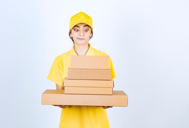 Una mujer bonita en uniforme amarillo con cajas de papel artesanal marrón en blanco.