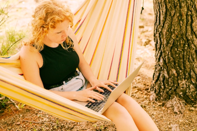 Mujer bonita usando laptop en hamaca